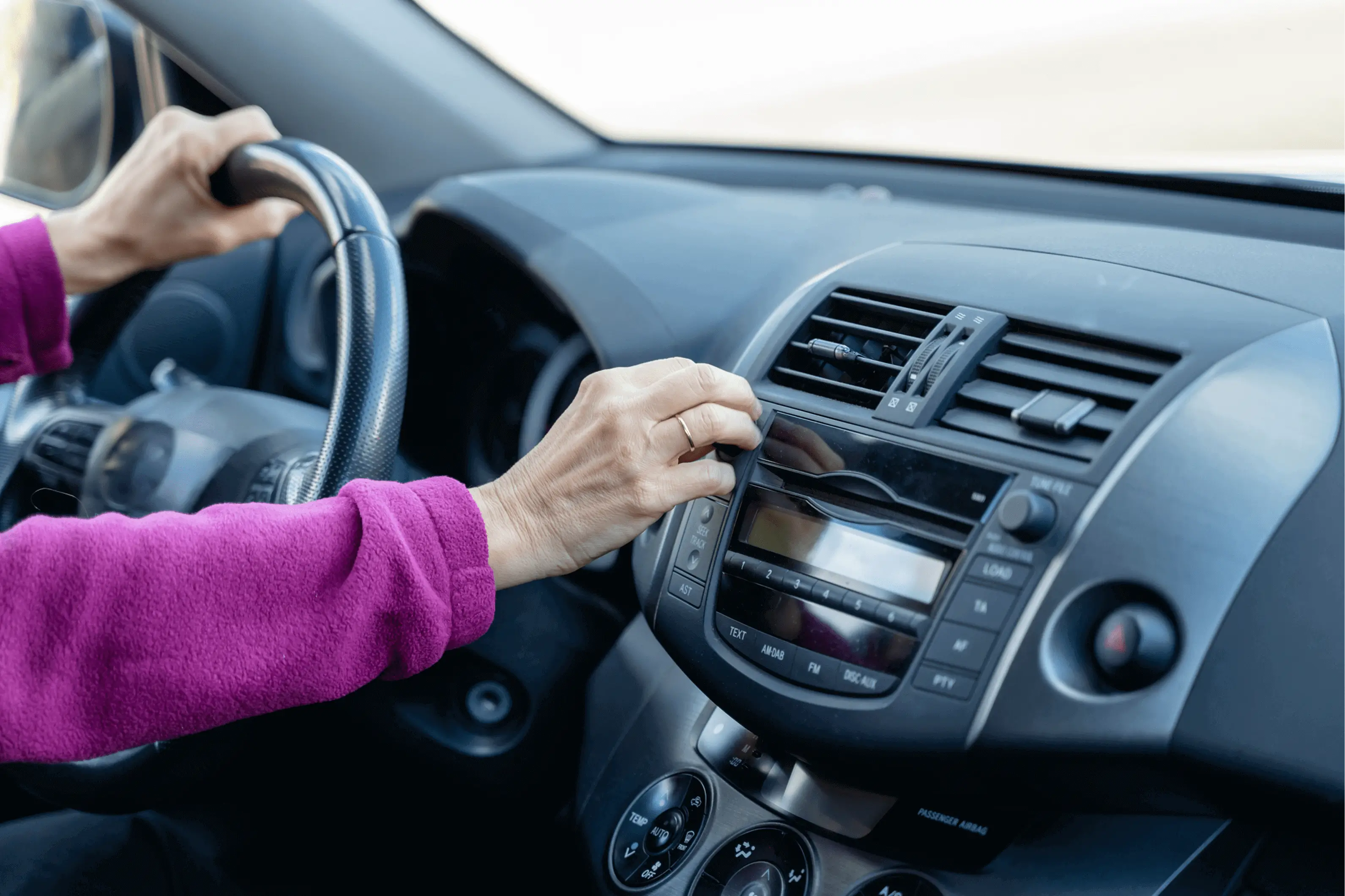 Person adjusting car stereo while driving.