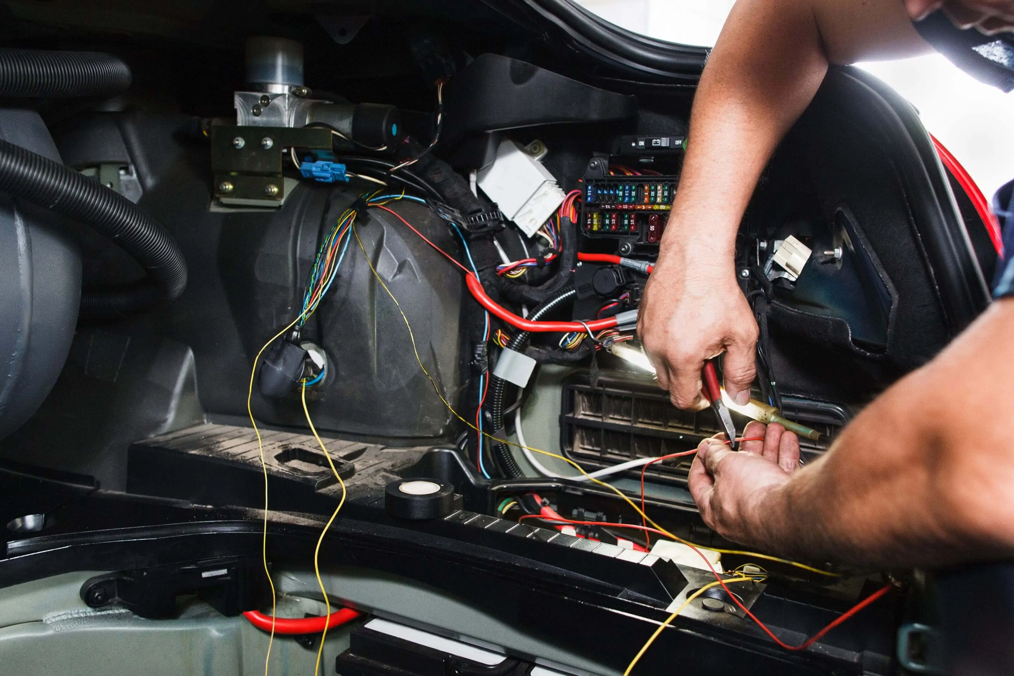 Mechanic working on vehicle electrical wiring.